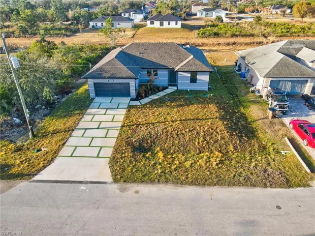 Ranch-style home featuring an attached garage, driveway, roof with shingles, and a residential view