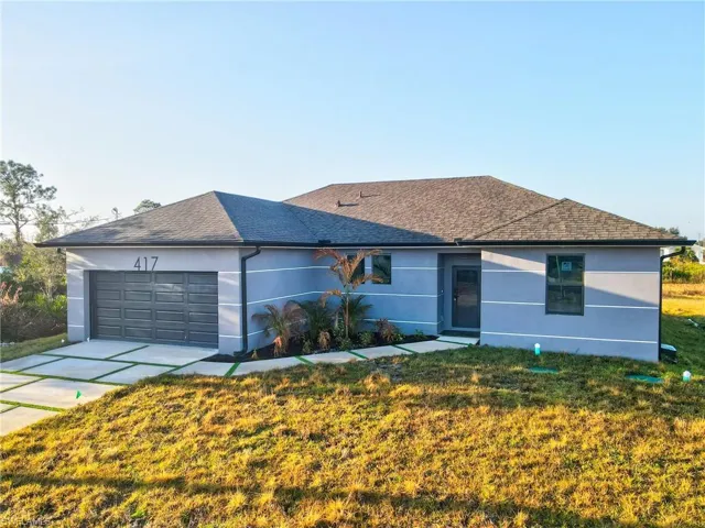 Single story home featuring stucco siding, a front lawn, an attached garage, and driveway