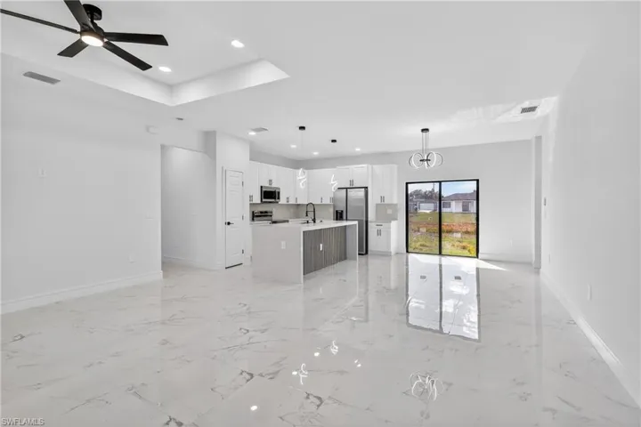 Kitchen featuring open floor plan, white cabinetry, an island with sink, and stainless steel appliances