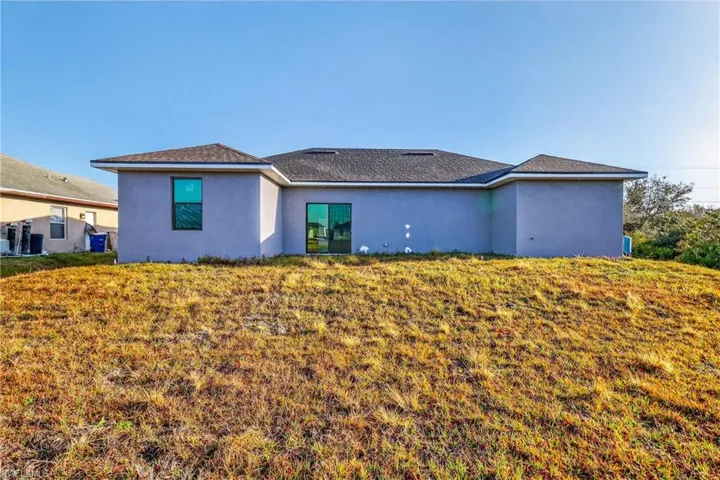 Rear view of property featuring stucco siding and a yard