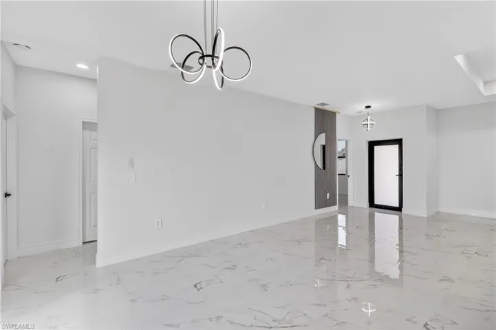 Unfurnished dining area with a chandelier and light marble finish flooring