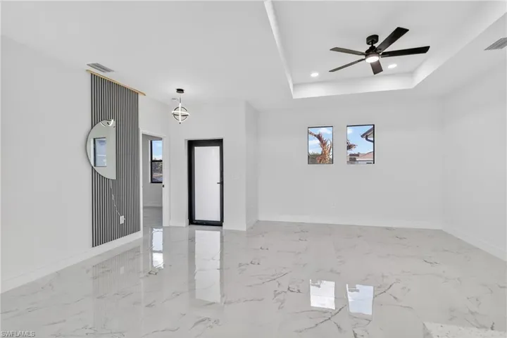 Entryway with healthy amount of natural light, ceiling fan, a raised ceiling, recessed lighting, and light marble finish floors