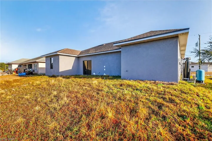 Back of property with stucco siding, a lawn, and a shingled roof