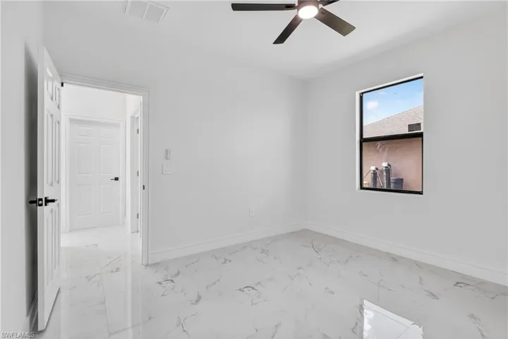 Spare room with light marble finish floors and ceiling fan