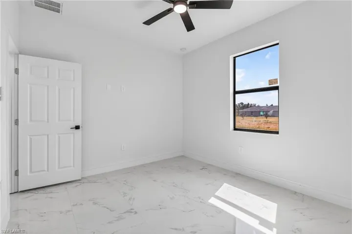 Empty room featuring light marble finish flooring and a ceiling fan