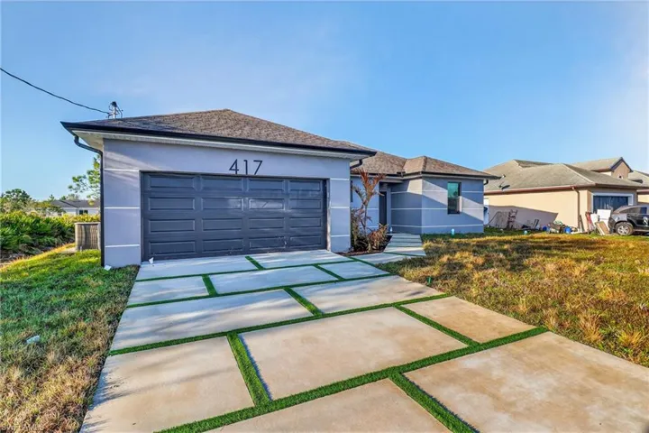 Ranch-style house with stucco siding, a garage, and driveway