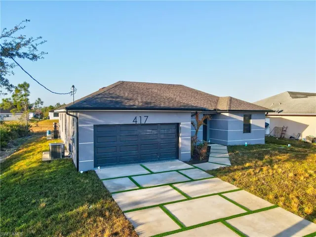 Ranch-style home featuring stucco siding, roof with shingles, a front lawn, and driveway