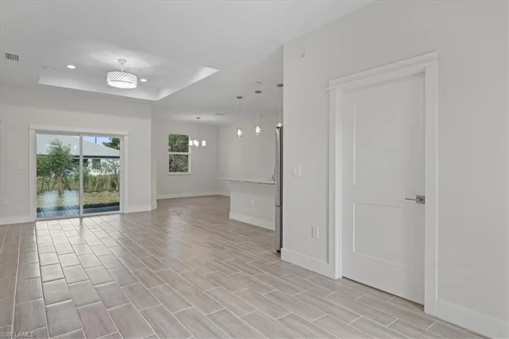 Spare room featuring a chandelier, a raised ceiling, recessed lighting, and wood tiled floors