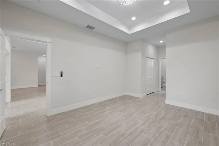 Unfurnished room featuring recessed lighting, a tray ceiling, and wood tiled floors