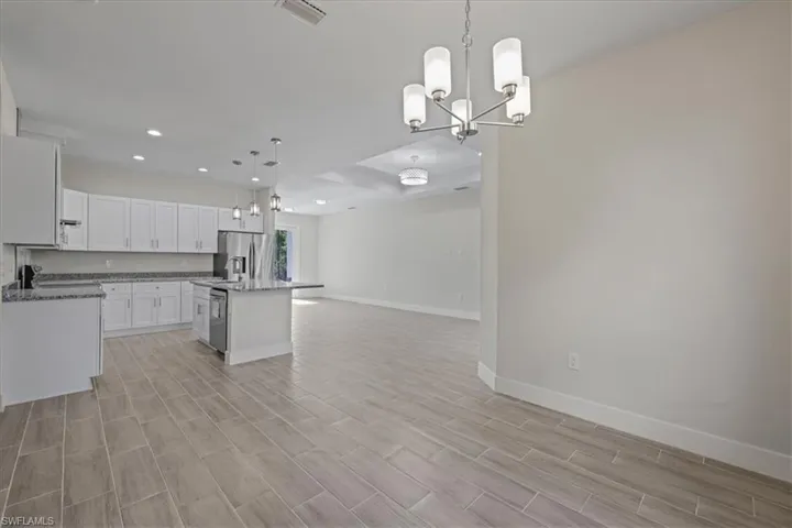 Kitchen with decorative light fixtures, recessed lighting, white cabinets, a kitchen island, and open floor plan