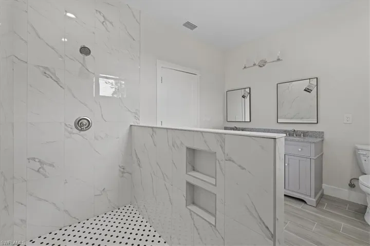 Full bathroom featuring a marble finish shower, vanity, and wood finish floors