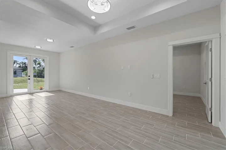 Unfurnished room featuring french doors, wood tiled floors, a tray ceiling, and recessed lighting