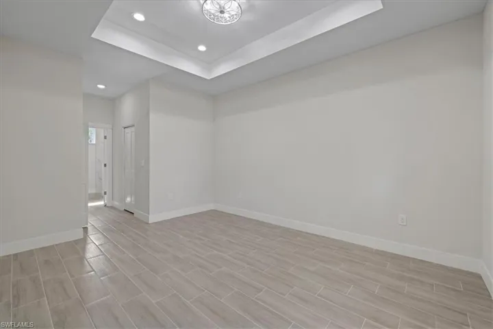Unfurnished room with a tray ceiling, recessed lighting, and wood finish floors