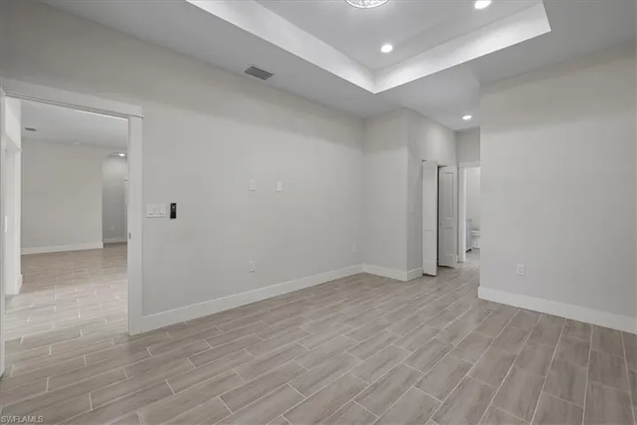 Spare room featuring recessed lighting, a tray ceiling, wood tiled floors, and arched walkways