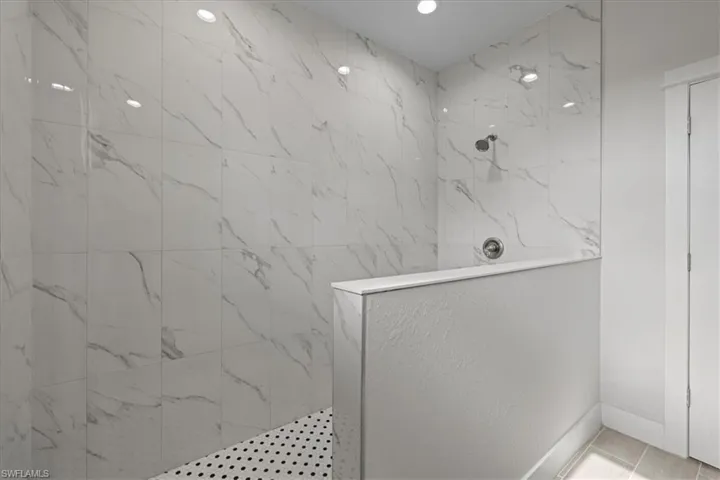 Bathroom featuring a marble finish shower and baseboards