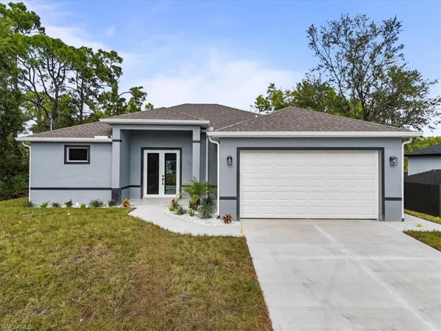 View of front of property featuring concrete driveway, a front yard, roof with shingles, an attached garage, and stucco siding