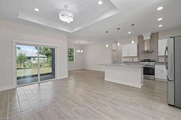 Kitchen featuring a chandelier, stainless steel appliances, a center island with sink, light stone countertops, and recessed lighting