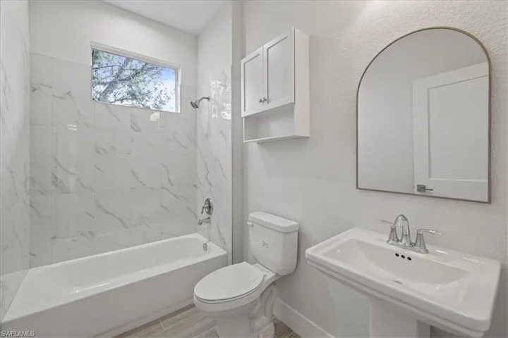 Bathroom with tub / shower combination and a textured wall