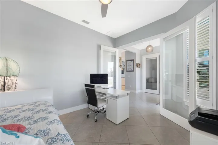 Bedroom with an office area, a ceiling fan, french doors, and light tile patterned floors