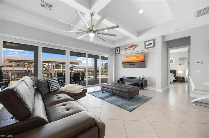 Living room featuring beam ceiling, ceiling fan, light tile patterned floors, coffered ceiling, and recessed lighting