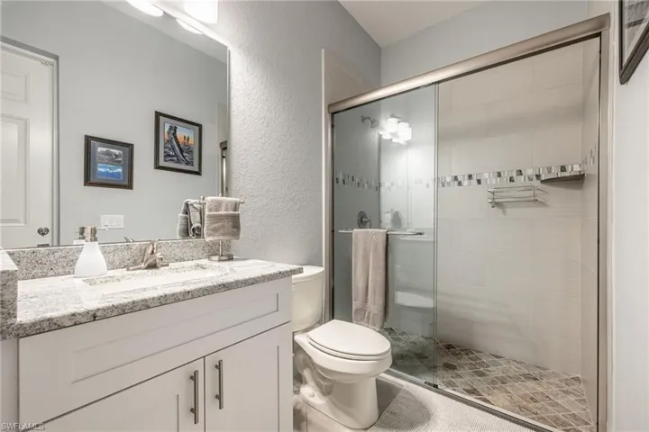 Bathroom with a textured wall, vanity, and a stall shower