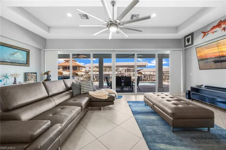 Tiled living room featuring a tray ceiling, healthy amount of natural light, and ceiling fan