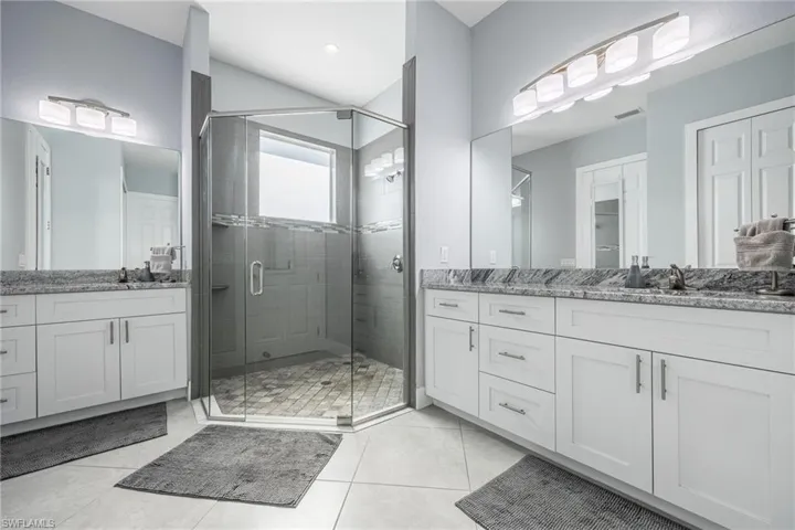 Full bathroom with two vanities, a stall shower, and light tile patterned floors