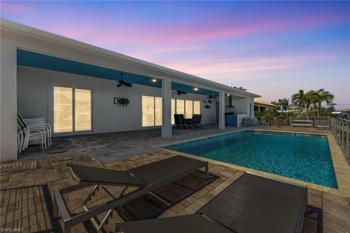 Pool at dusk with a patio area and outdoor dining space