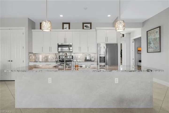 Kitchen featuring light tile patterned floors, white cabinets, tasteful backsplash, stainless steel appliances, and recessed lighting