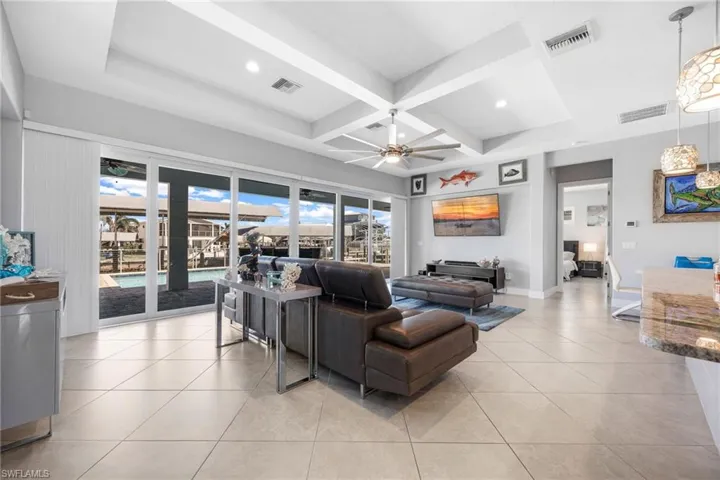 Living area with coffered ceiling, a ceiling fan, light tile patterned flooring, beamed ceiling, and recessed lighting