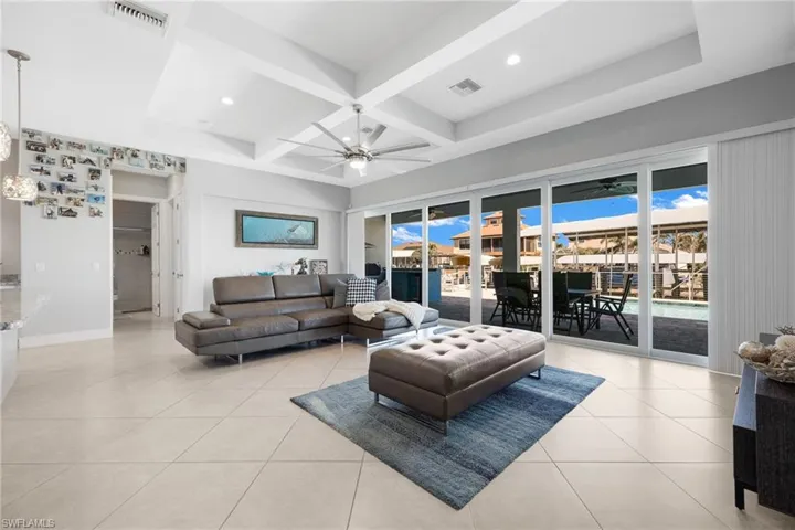 Living area featuring coffered ceiling, beam ceiling, recessed lighting, light tile patterned flooring, and ceiling fan