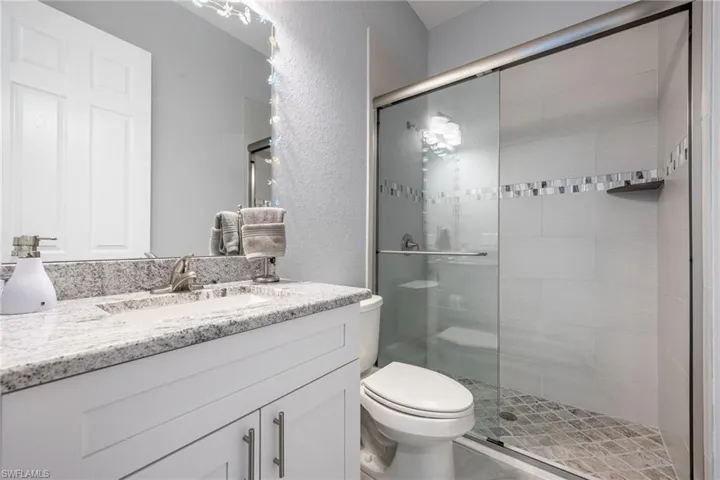 Bathroom featuring vanity, a textured wall, and a shower stall
