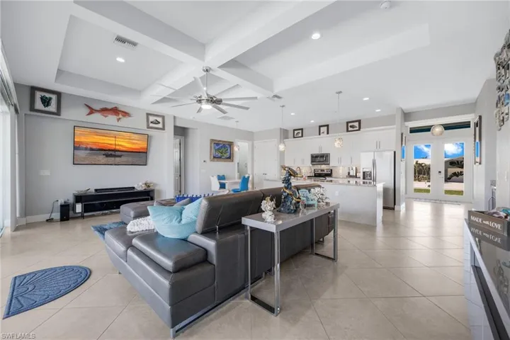Living area with coffered ceiling, beam ceiling, recessed lighting, ceiling fan, and french doors