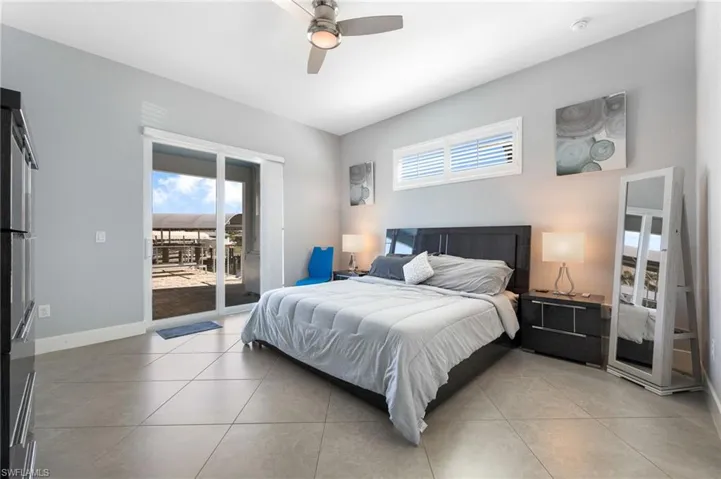 Bedroom featuring multiple windows, access to exterior, a ceiling fan, and light tile patterned flooring