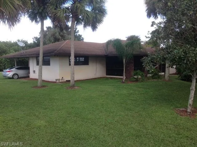 View of side of property with an attached carport, a yard, and stucco siding