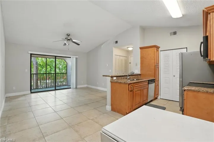 Kitchen featuring appliances with stainless steel finishes, ceiling fan, lofted ceiling, brown cabinetry, and open floor plan