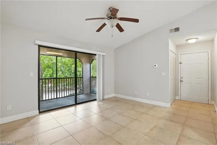 Spare room with vaulted ceiling, light tile patterned floors, and a ceiling fan