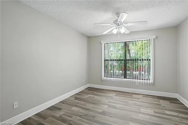 Empty room featuring wood finished floors, ceiling fan, and a textured ceiling