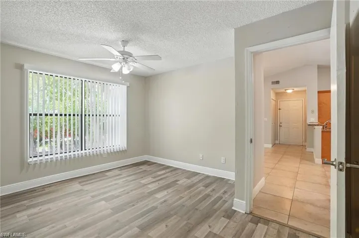 Unfurnished room with a ceiling fan, light wood finished floors, and a textured ceiling