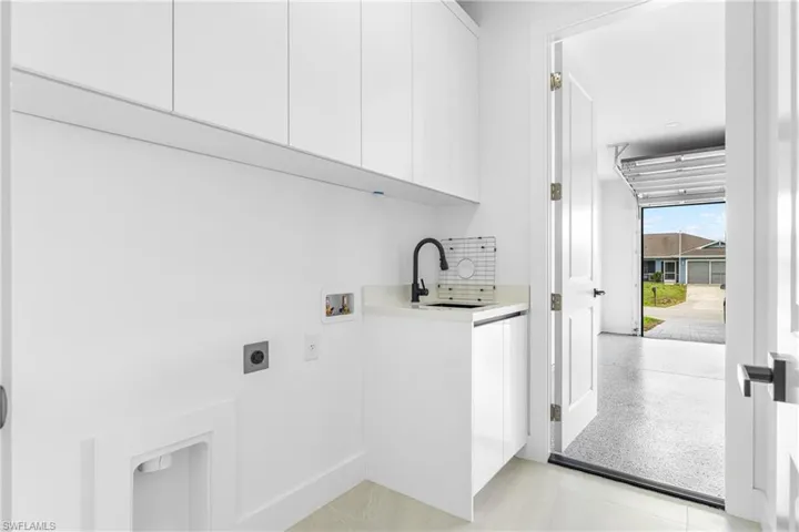 Bright utility room featuring ample white cabinetry, a dedicated sink with a matte black faucet, and a light-toned countertop