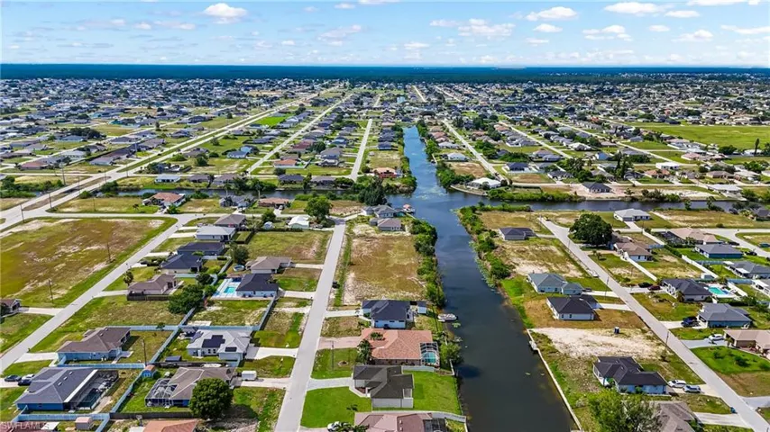 Expansive residential area featuring numerous single-story homes, a canal system, paved roads, and various vacant land parcels