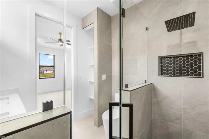 Contemporary shower enclosure featuring a ceiling-mounted rain showerhead, hexagonal tile niche, and glass paneling