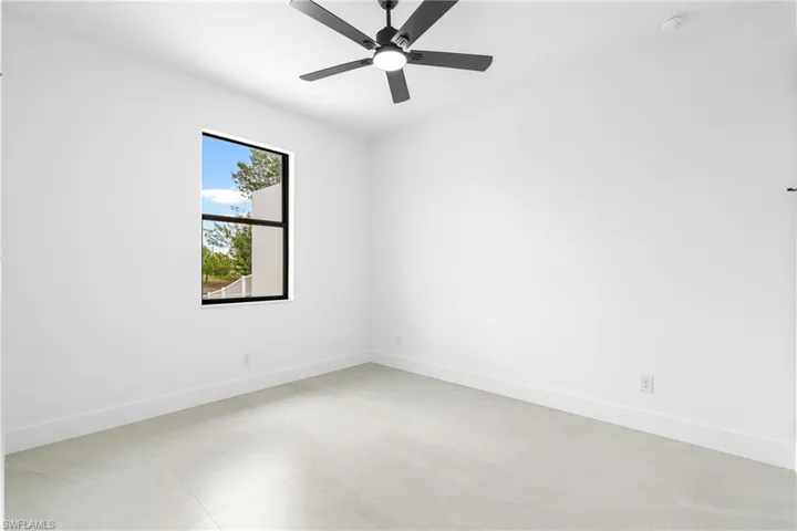 Room featuring a black ceiling fan, white walls, and light-toned tile flooring