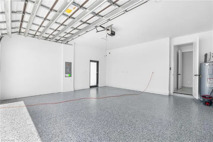 Garage interior featuring an epoxy coated concrete floor, white painted walls, and an overhead garage door mechanism