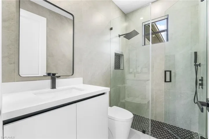 Contemporary bathroom featuring a floating vanity with integrated sink, matte black fixtures, and a frameless glass shower enclosure