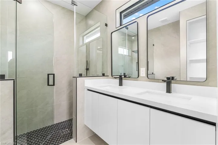Modern bathroom featuring a frameless glass shower enclosure with hex tile flooring