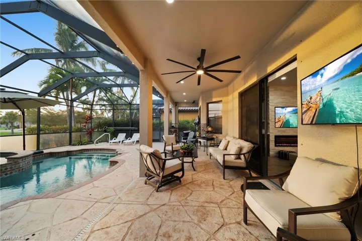 View of patio featuring screen enclosure, a ceiling fan, a pool with connected hot tub, and an outdoor living space