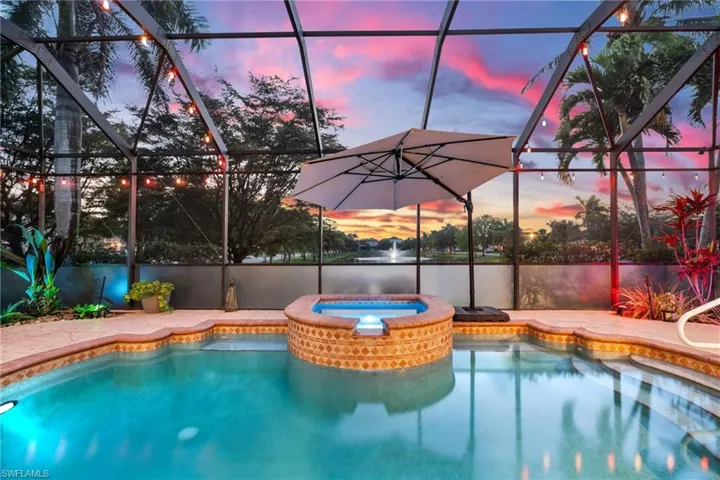 View of swimming pool featuring glass enclosure and a pool with connected hot tub