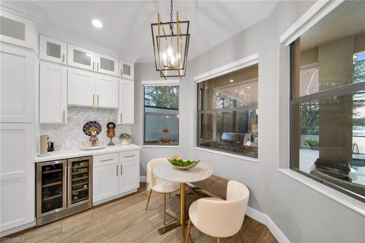 Bar featuring wine cooler, a bar, light wood-style floors, baseboards, and tasteful backsplash