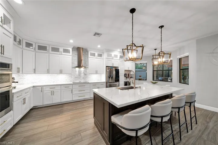 Kitchen with wall chimney exhaust hood, stainless steel appliances, a sink, recessed lighting, and decorative backsplash